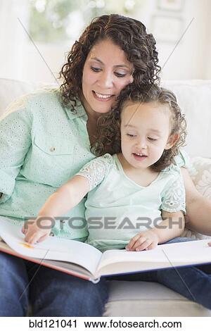 Stock Image - Mixed race mother reading with daughter. Fotosearch
