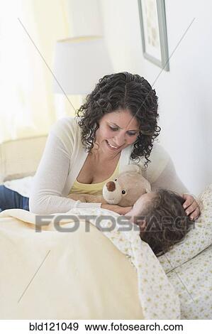 Mixed race mother tucking daughter and teddy bear into bed View Large Photo Image Stock Photo - Mixed race mother tucking daughter and teddy bear into bed. Fotosearch