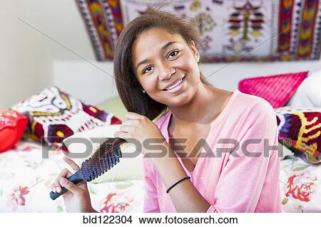 Mixed race teenage girl brushing hair in bedroom View Large Photo Image Picture - Mixed race teenage girl brushing hair in bedroom. Fotosearch