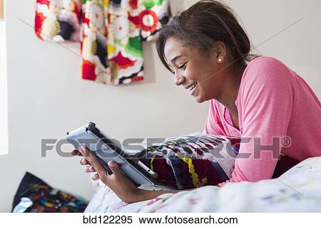 Mixed race teenage girl using digital tablet on bed View Large Photo Image Stock Photography - Mixed race teenage girl using digital tablet on bed. Fotosearch