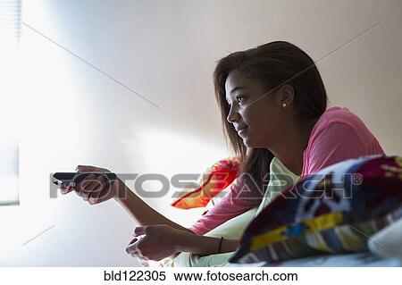 Mixed race teenage girl watching television on bed View Large Photo Image Stock Photography - Mixed race teenage girl watching television on bed. Fotosearch