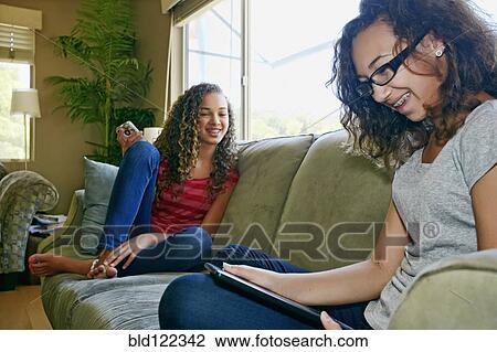 Mixed race teenage girls relaxing on sofa View Large Photo Image Stock Image - Mixed race teenage girls relaxing on sofa. Fotosearch