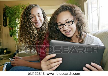 Mixed race teenage girls relaxing on sofa View Large Photo Image Stock Image - Mixed race teenage girls relaxing on sofa. Fotosearch