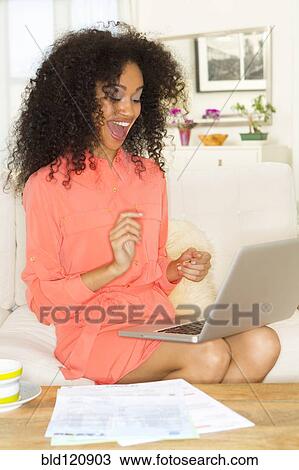 Mixed race woman cheering at laptop View Large Photo Image Stock Image - Mixed race woman cheering at laptop. Fotosearch