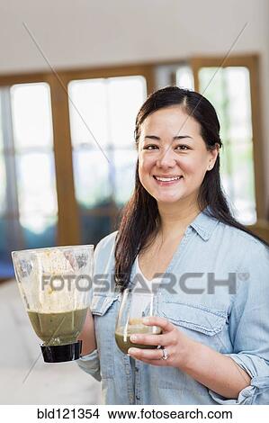 Picture - Mixed race woman drinking green smoothie. Fotosearch