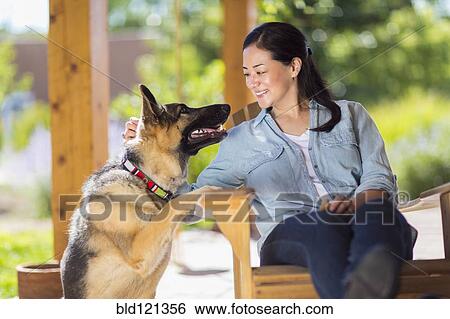 Stock Photograph - Mixed race woman petting dog. Fotosearch