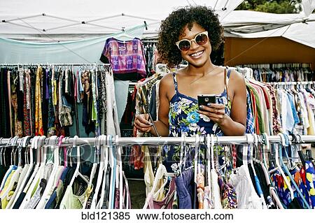 Stock Photography - Mixed race woman shopping at flea market. Fotosearch