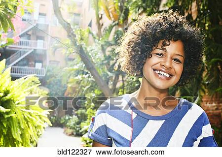 Stock Photo - Mixed race woman smiling in courtyard. Fotosearch