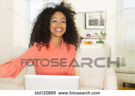 Stock Photo - Mixed race woman smiling in living room. Fotosearch