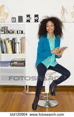 Picture - Mixed race woman using digital tablet. Fotosearch