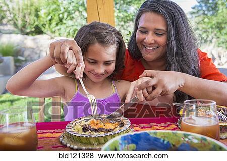 Stock Photo - Mother and daughter eating at table. Fotosearch