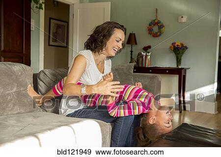 Stock Photo - Mother and daughter playing in living room. Fotosearch
