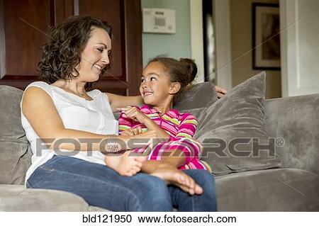 Stock Image - Mother and daughter relaxing on sofa. Fotosearch