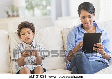 Stock Image - Mother and son relaxing on sofa. Fotosearch