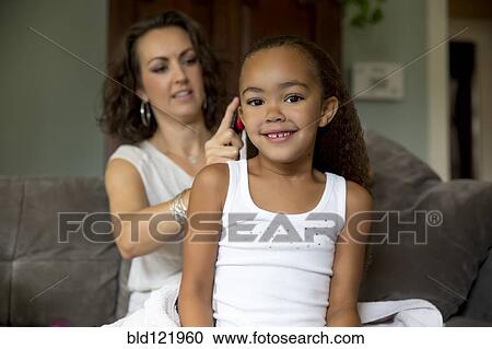 Stock Image - Mother fixing daughter's hair. Fotosearch
