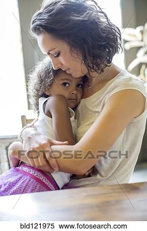 Stock Photography - Mother holding daughter at table. Fotosearch