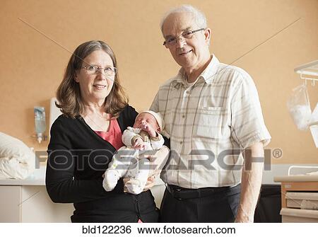 Stock Photograph - Senior Caucasian couple holding newborn grandson. Fotosearch