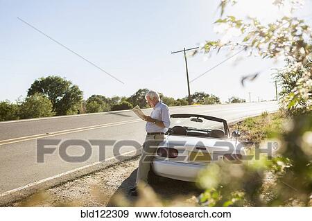 Stock Photo - Senior Caucasian man reading map by road. Fotosearch