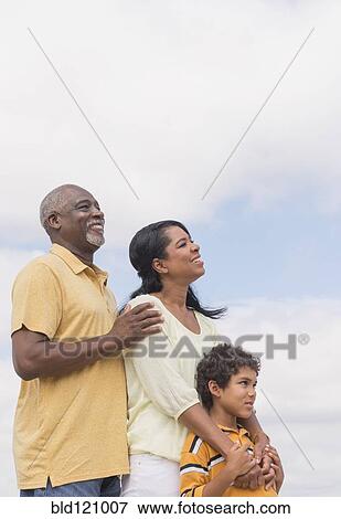 Stock Photo - Three generations of family smiling outdoors. Fotosearch
