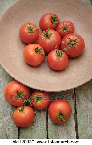 Stock Image - Tomatoes in bowl on wooden table. Fotosearch