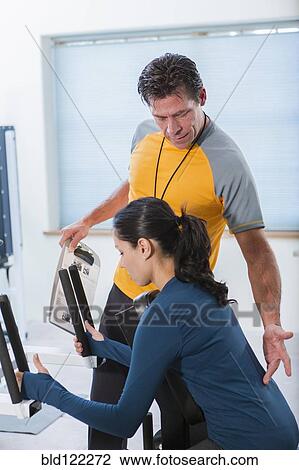Stock Image - Woman working with personal trainer in gym. Fotosearch