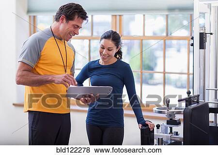 Stock Photo - Woman working with personal trainer in gym. Fotosearch