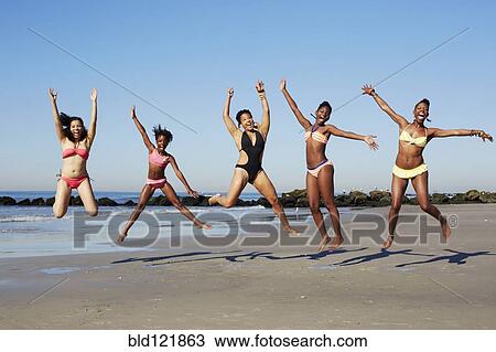Stock Image - Women jumping for joy on beach. Fotosearch
