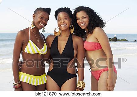 Stock Image - Women smiling together on beach. Fotosearch