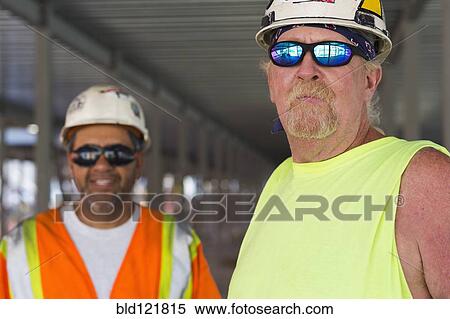 Stock Photography - Workers smiling together at construction site. Fotosearch