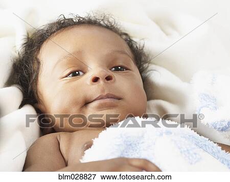 Stock Photo - Black baby laying on bed. Fotosearch