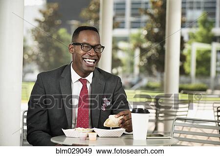 Stock Photo - Black businessman eating at cafe. Fotosearch