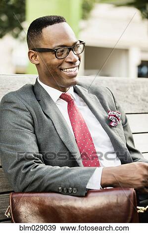 Stock Photo - Black businessman sitting on park bench. Fotosearch