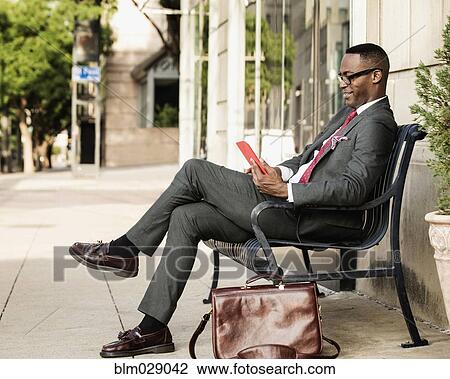 Black businessman using digital tablet on bench View Large Photo Image Stock Image - Black businessman using digital tablet on bench. Fotosearch