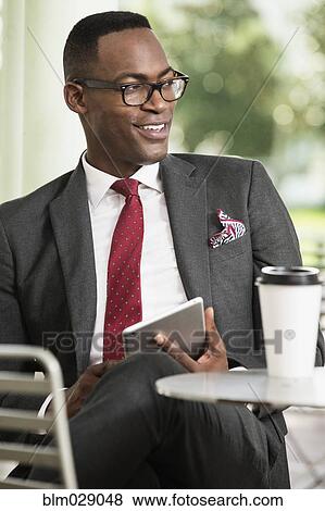Black businessman using digital tablet at cafe View Large Photo Image Stock Photo - Black businessman using digital tablet at cafe. Fotosearch