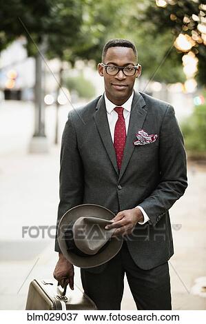Stock Photo - Black businessman walking on city street. Fotosearch