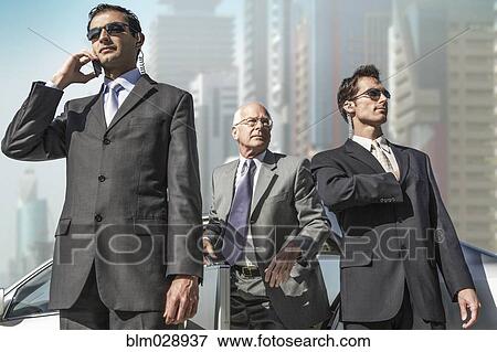 Stock Photo - Bodyguards protecting businessman on city street. Fotosearch