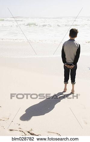 Boy standing on sunny beach View Large Photo Image Stock Image - Boy standing on sunny beach. Fotosearch