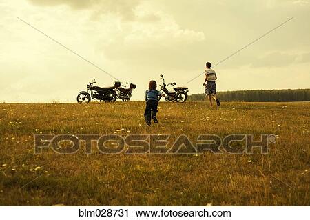 Boys running to motorcycles in rural landscape View Large Photo Image Stock Image - Boys running to motorcycles in rural landscape. Fotosearch