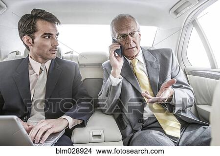 Picture - Businessmen working in backseat of car. Fotosearch