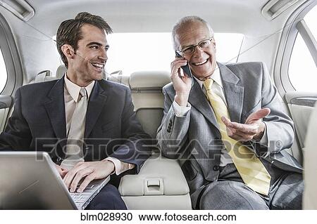 Stock Image - Businessmen working in backseat of car. Fotosearch