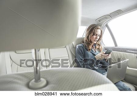 Businesswoman working in backseat of car View Large Photo Image Stock Image - Businesswoman working in backseat of car. Fotosearch