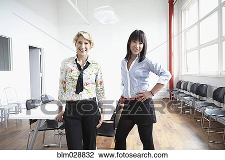 Stock Image - Businesswomen smiling in office. Fotosearch