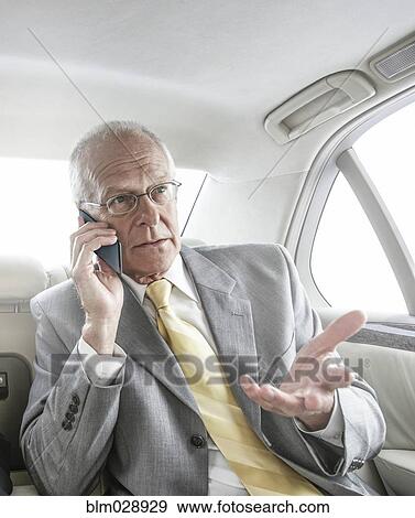 Stock Photo - Caucasian businessman talking on cell phone in car. Fotosearch