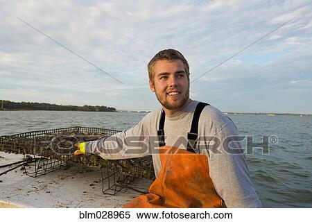 Stock Photography - Caucasian fisherman holding net on boat. Fotosearch