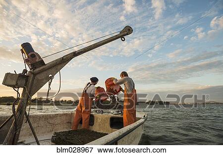 Stock Photo - Caucasian fishermen throwing bait into water. Fotosearch