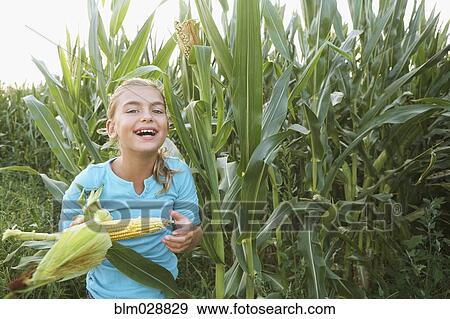 Stock Photo - Caucasian girl eating corn in field. Fotosearch