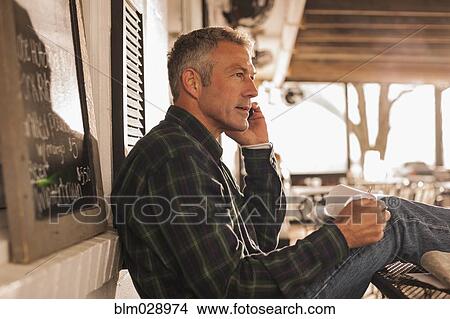 Caucasian man talking on cell phone on patio View Large Photo Image Picture - Caucasian man talking on cell phone on patio. Fotosearch