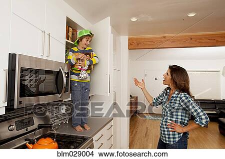 Picture - Caucasian mother scolding son on counter top. Fotosearch