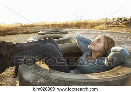 Caucasian teenage girl sitting in empty tire View Large Photo Image Stock Photo - Caucasian teenage girl sitting in empty tire. Fotosearch
