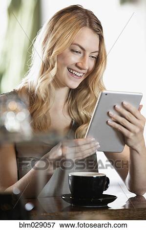 Stock Photo - Caucasian woman using digital tablet in cafe. Fotosearch